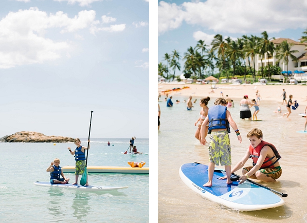 Kids playing on a paddle board on the beach in Ko Olina