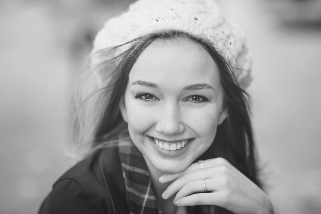 Girl in knit cap with hand under chin smiling at the camera