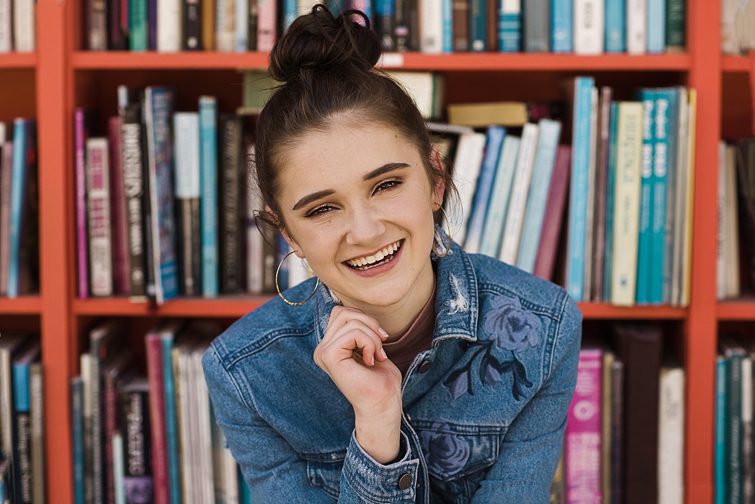 Girl in jean jacket sitting in front of bookshelf outside of Ken Sanders Book Store