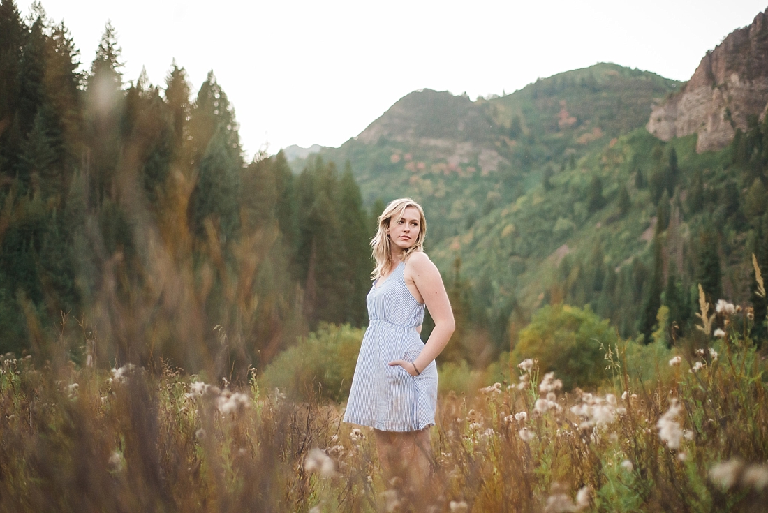 Girl in blue summer dress standing in field in big cottonwood canyon