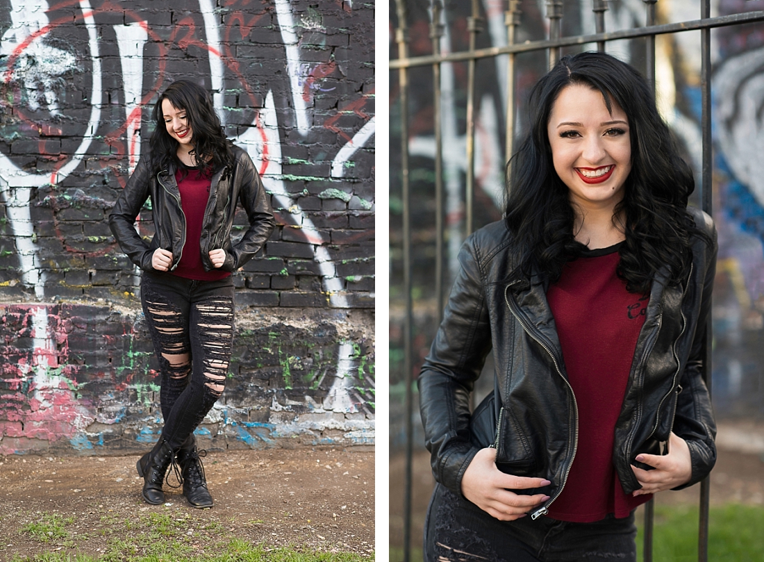 Senior Portraits in a leather jacket and ripped black jeans standing in front of a graffiti wall