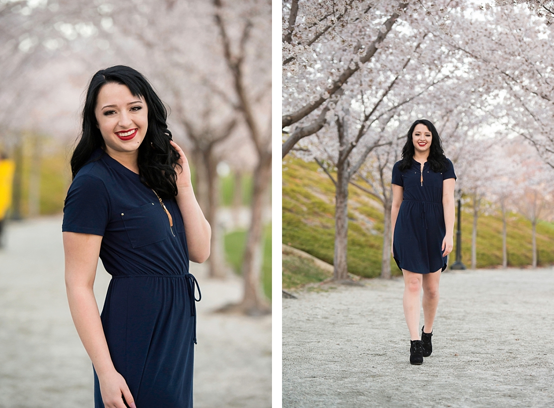 Girl in navy blue dress walking a path lined with pink blossoms at the utah state capitol building