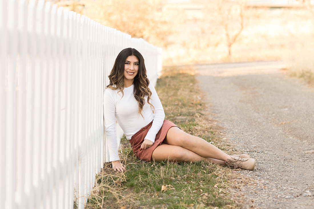 Rock Springs High School Senior Portraits of girl sitting by white picket fence