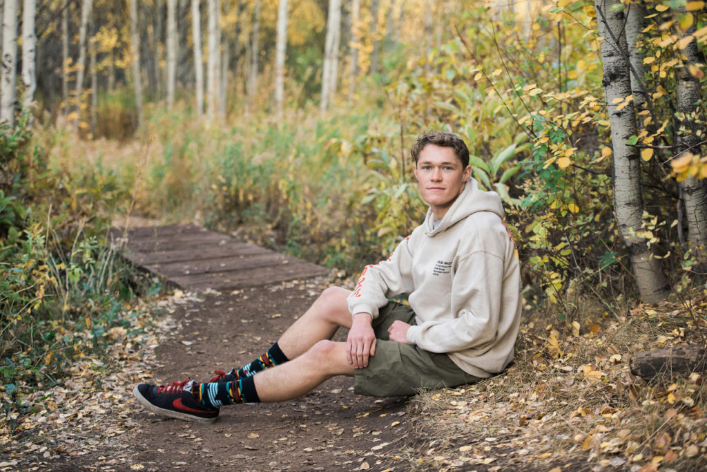 Park City High School boy sitting on trail by aspen trees