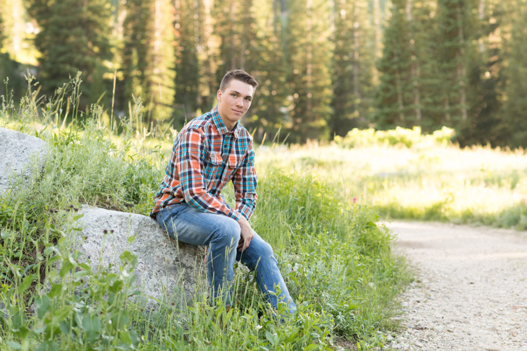 Amanda Nelson Photography boy in plaid shirt sitting on rock in the mountains