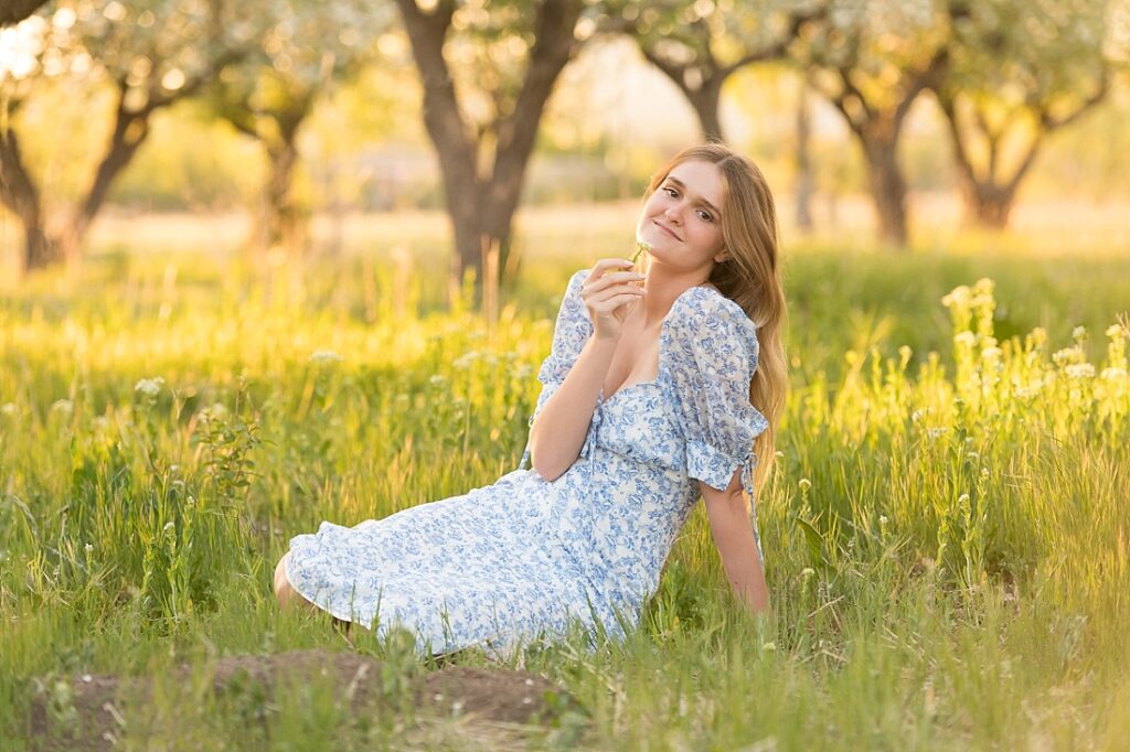 Olympus High School Graduate sitting in the spring grass in an orchard
