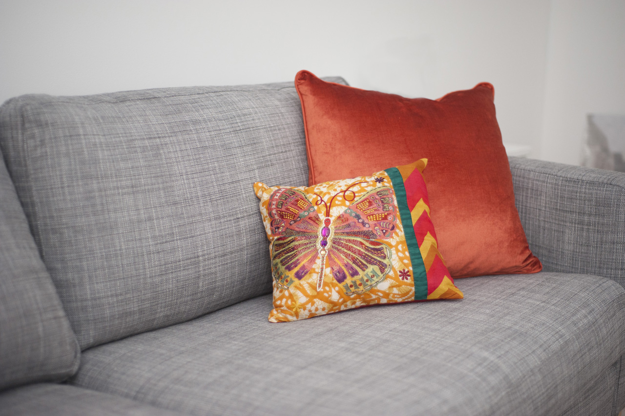 Gray couch with a butterfly pillow and orange velvet pillow | Amanda Nelson Photography