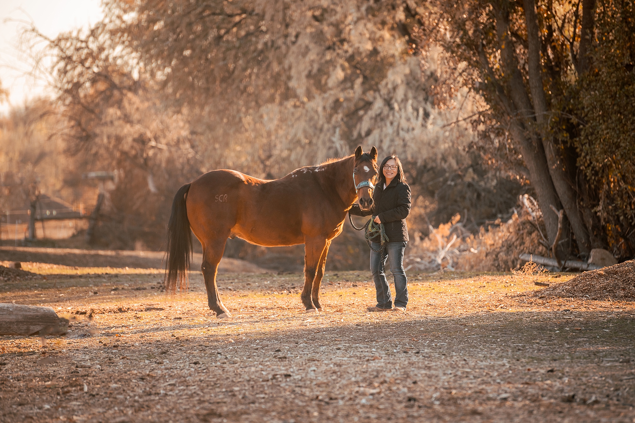 Equestrian standing with her horse in the fall leaves