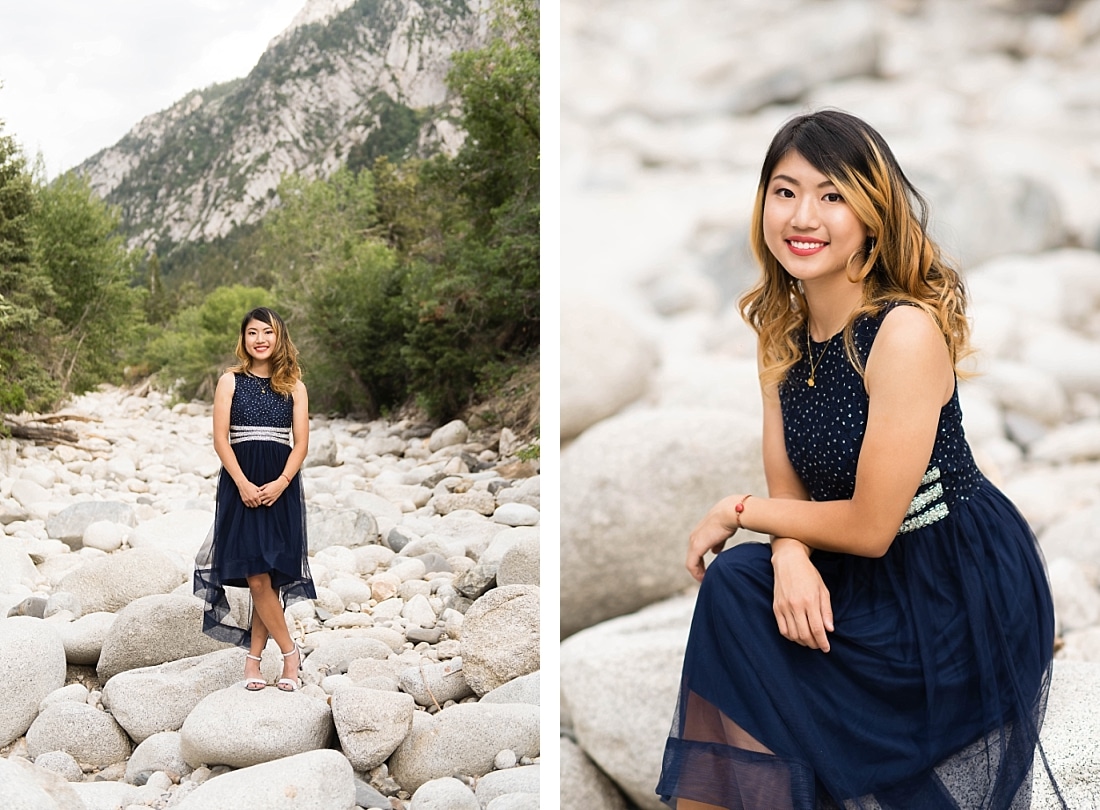 Girl in a navy blue dress standing in a dry riverbed with mountain in background.