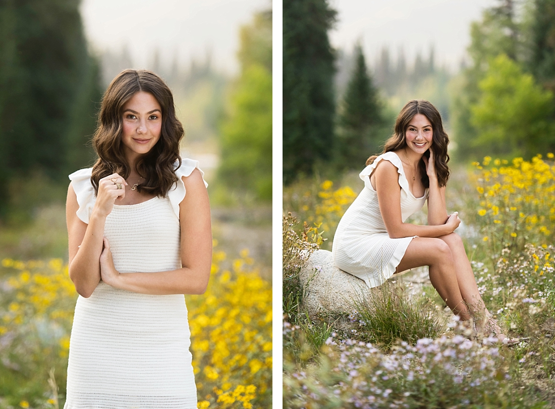 Girl in white dress sitting on a stone in wildflowers.
