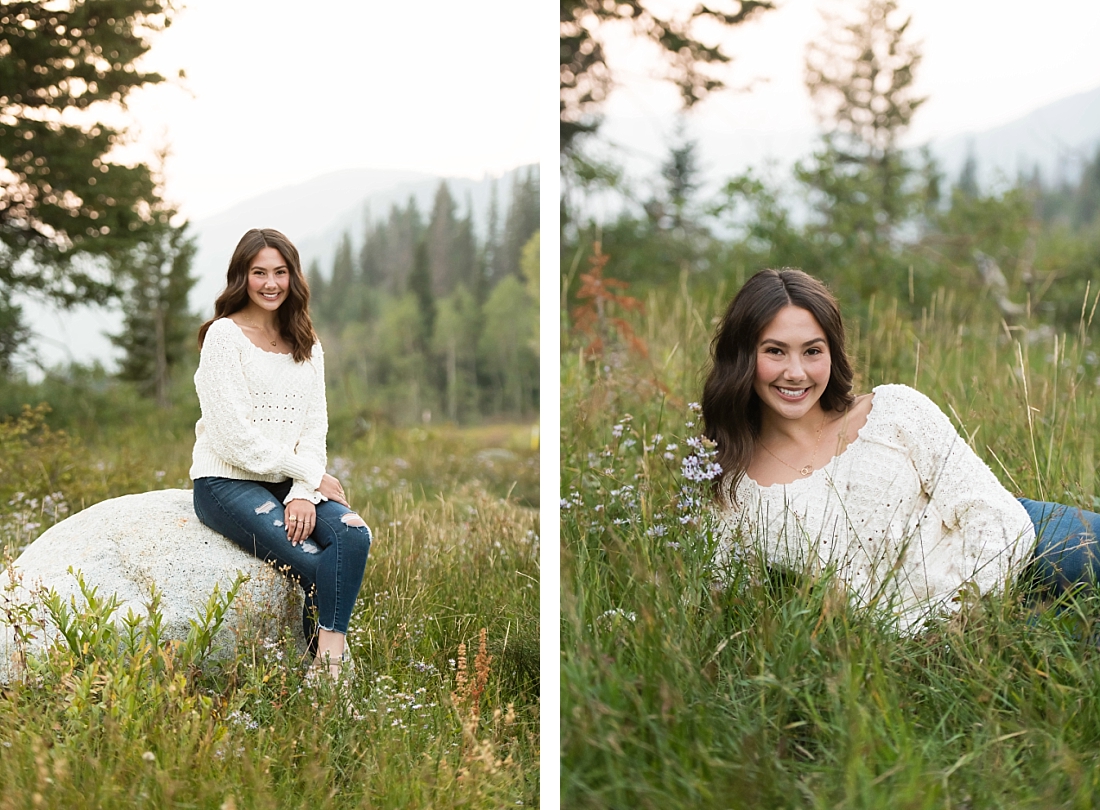 Girl with brown hair wearing a cream sweater sitting on a rock in the mountains.